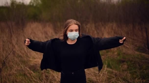 La donna in una maschera si mette una giacca a pandemia di natura covid-19 Coronavirus — Video Stock