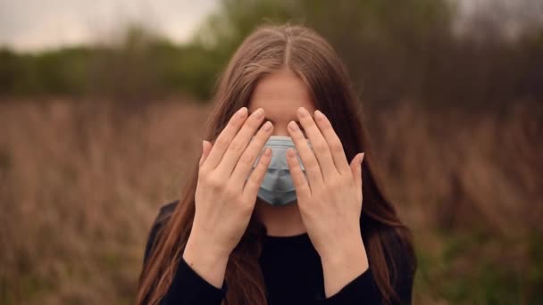 Mujer con máscara médica cierra y abre la cara con las manos pandémica covid-19 Coronavirus — Vídeos de Stock
