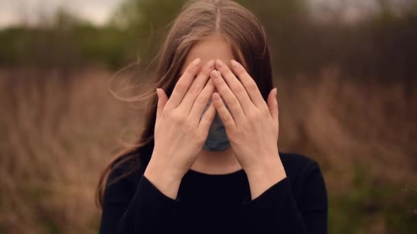 Frau in medizinischer Maske schließt und öffnet Gesicht mit Händen pandemischen Covid-19 Coronavirus — Stockvideo