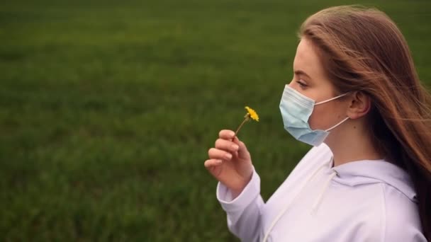 Donna attraverso una maschera annusa un fiore giallo dente di leone pandemia covid-19 — Video Stock