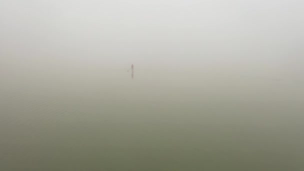 Samotář se vznáší na prkně na řece ve velmi husté mlze — Stock video
