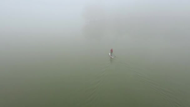 Un uomo solo galleggia su una tavola su un fiume in una nebbia molto fitta — Video Stock