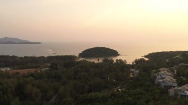 İnsansız hava aracı gün batımından sonra orman ve deniz üzerinde uçuyor.