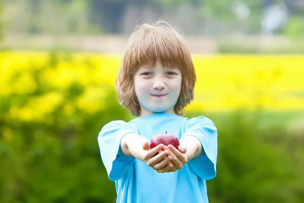 Menino com maçã vermelha no jardim — Fotografia de Stock