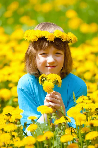 Niño con corona de flores en el campo — Foto de Stock