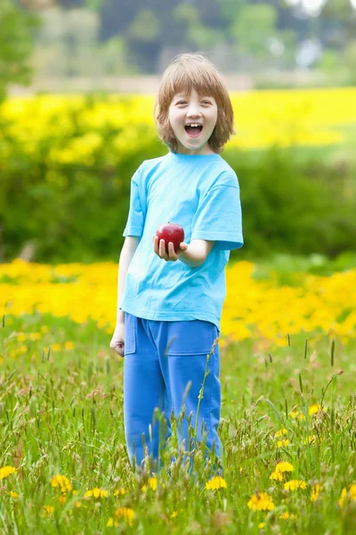 Niño con manzana roja en el jardín — Foto de Stock