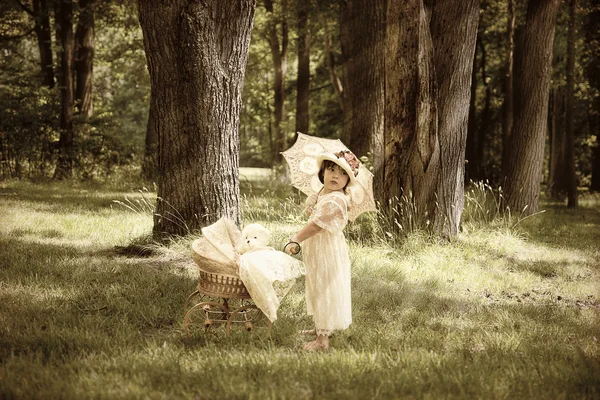 Gamla mode ung flicka med docka Buggy i Forrest — Stockfoto