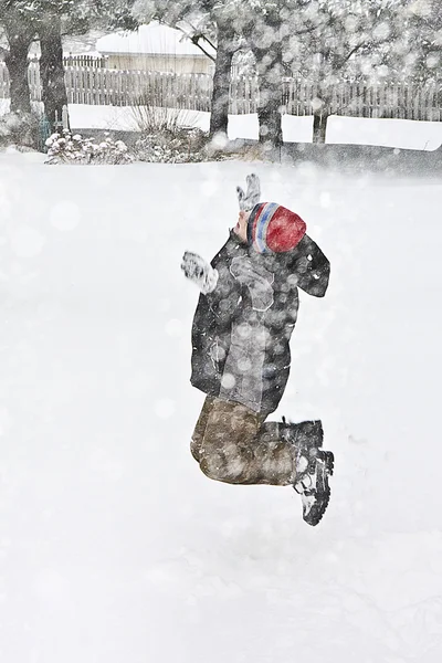 Giovane ragazzo che gioca nel bel mezzo di una bufera di neve - Salto — Foto Stock