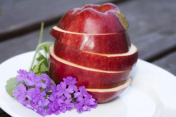 Ενιαίο κόκκινο νόστιμο μήλο κομμένο σε φέτες με λουλούδι — Φωτογραφία Αρχείου