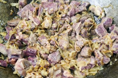 Soğan ve et parçalarını bir kazanda ihtiva eder