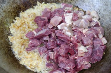 Soğan ve et parçalarını bir kazanda ihtiva eder