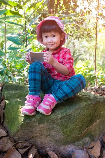 Asiático hermosa chica usando inteligente phone en boulder sobre naturaleza fondo . — Foto de Stock