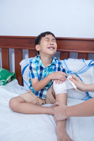 Kind verletzt. Mutter bandagiert Sohn das Knie. — Stockfoto