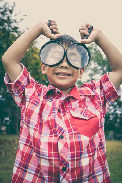 Jeune garçon explorant la nature avec une loupe. À l'extérieur . — Photo