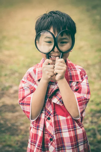 少年は虫眼鏡で自然を探索します。アウトドア. — ストック写真