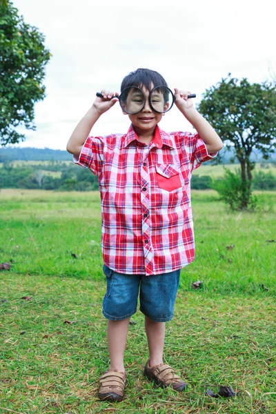 完全なボディ。少年は虫眼鏡で自然を探索します。屋外で一日の時間. — ストック写真