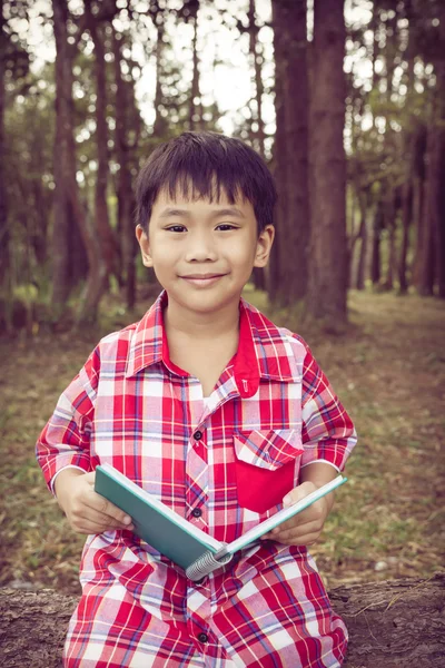 Menino asiático sorrindo e segurando um livro. Conceito de educação. Estilo vintage . — Fotografia de Stock