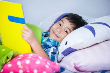 Asyalı çocuk kitap okuyorum. Eğitim kavramı.