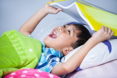 Asyalı çocuk şaşırmış, çocuk kitap ile baş kapsayan. 