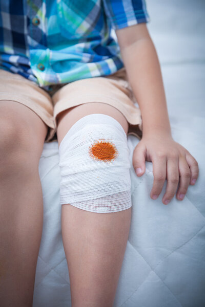 Child injured. Wound on the child's knee with bandage.