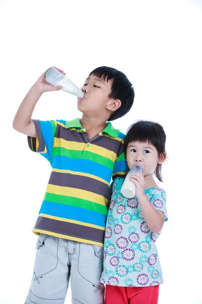 Dos chicos y chicas asiáticos bebiendo leche, sobre blanco. Beber leche —  Fotos de Stock