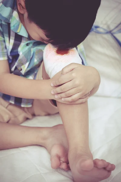 Chiudete. Bambino ferito. Ferito sul ginocchio del bambino con benda . — Foto Stock