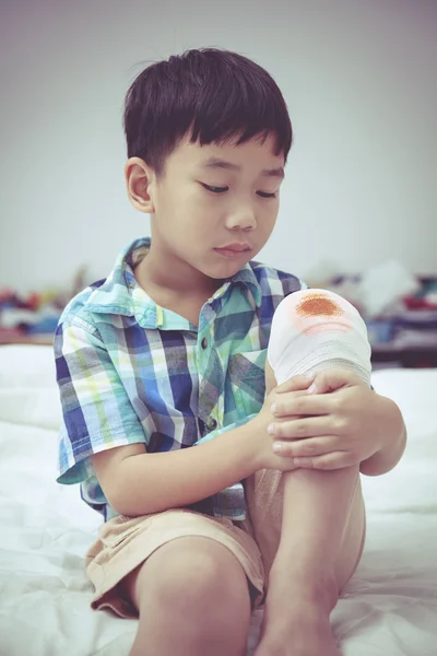 Barn skadas. Sår på barnets knä med bandage. Vintage tonen. — Stockfoto
