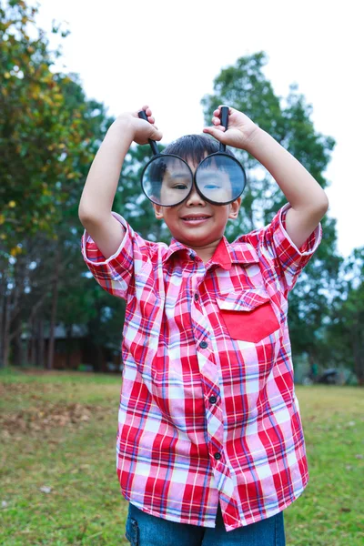 Young boy exploring nature with magnifying glass. Outdoors. — Stock Photo, Image