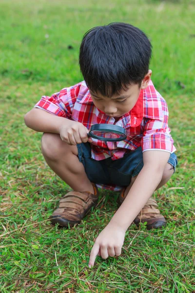 少年は虫眼鏡で自然を探索します。アウトドア. — ストック写真