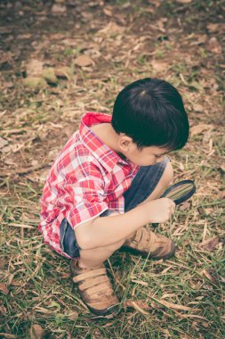 Genç çocuk doğa büyüteç ile keşfetmek. Açık havada. Retro tarzı.