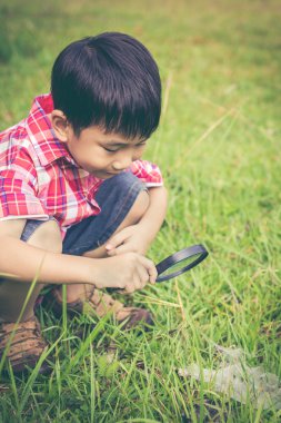 Genç çocuk doğa büyüteç ile keşfetmek. Açık havada. Retro tarzı.