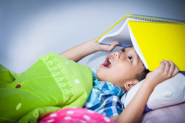 Asiático menino surpreso, criança cobrindo cabeça com livro . — Fotografia de Stock