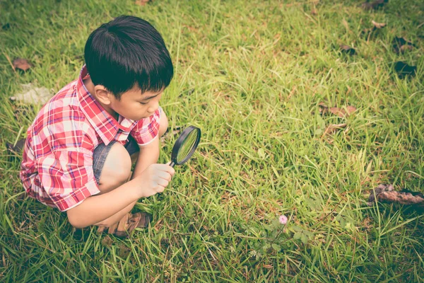 Jonge jongen verkennen van de natuur met vergrootglas. Buitenshuis. Retro stijl. — Stockfoto