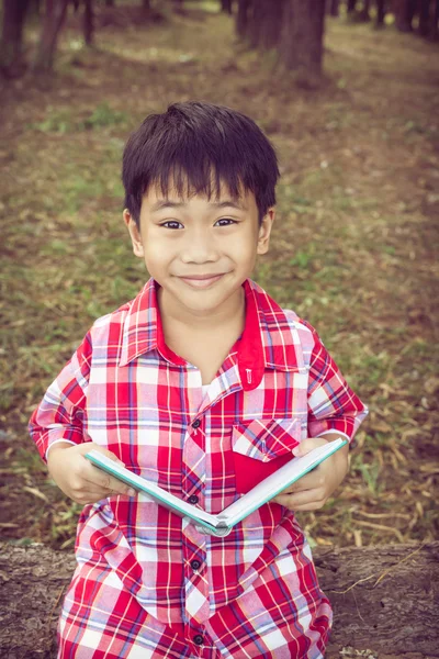 Azjatycki chłopiec uśmiecha się i trzyma książkę. Koncepcja edukacji. Dźwięk w Vintage — Zdjęcie stockowe