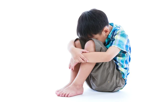 Kleiner trauriger Junge barfuß auf dem Boden sitzend. isoliert auf weißem Hintergrund. — Stockfoto