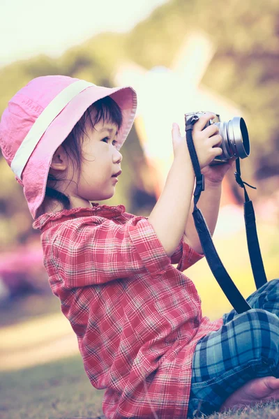 Aziatische meisje dat neemt foto's met behulp van vintage filmcamera in tuin. — Stockfoto
