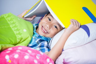 Yakın çekim. Asyalı çocuk Merkez kitap ve gülümseyen kapsayan. Eğitim kavramı.