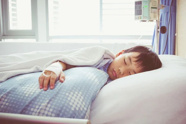 Азиатский мальчик лежит на больном с физраствором внутривенно (IV). Здравоохранение и люди . — стоковое фото