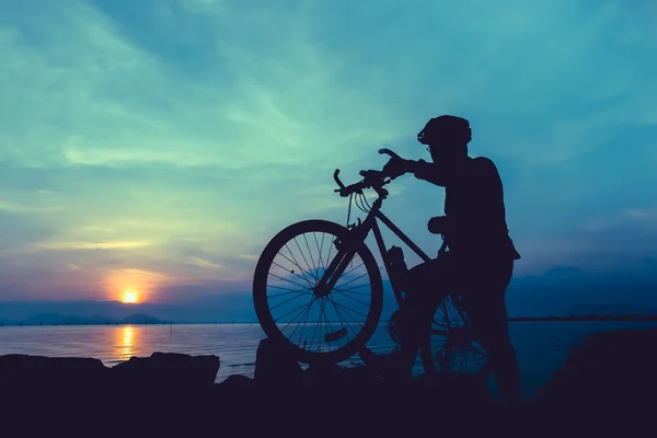 Gesunder Lebensstil. Silhouette eines Radfahrers, der mit Fahrrad am Meer steht. — Stockfoto