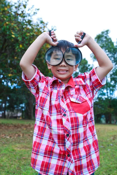 Jonge jongen verkennen van de natuur met vergrootglas. Buitenshuis. — Stockfoto