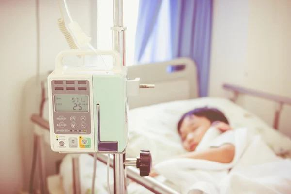Asiático menino deitado no leito doente com bomba de infusão intravenosa IV gotejamento — Fotografia de Stock