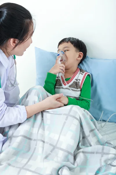 Asian boy having respiratory illness helped by health professional with inhaler. — Stock Photo, Image