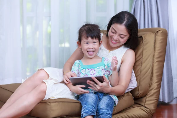 Mother and daughter using digital tablet. Family spending time together at home.