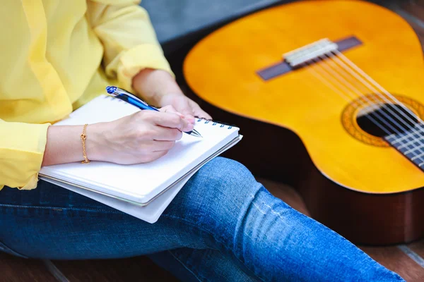 Τραγουδοποιός closeup εγγράφως σχετικά με Σημείωση χαρτί με ακουστική κιθάρα κοντά από. — Φωτογραφία Αρχείου