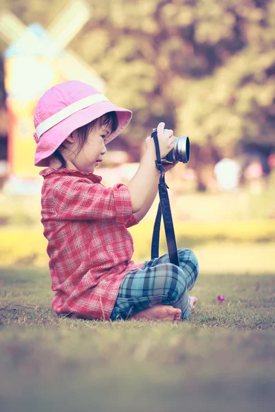 Aziatische meisje dat neemt foto's met behulp van vintage filmcamera in tuin. Vintage stijl. — Stockfoto