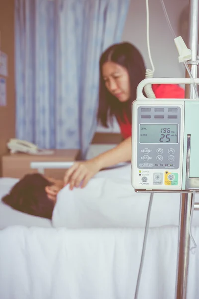 Asyalı çocuk hasta yatağının üzerinde infüzyon pompa intravenöz IV damlalıkla yalan — Stok fotoğraf