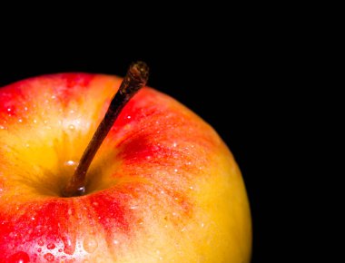 Su damlacıkları ile kırmızı lezzetli elmanın yakın çekimi. Siyah arka planda izole edilmiş. Vejetaryenler için sağlıklı yiyecekler.