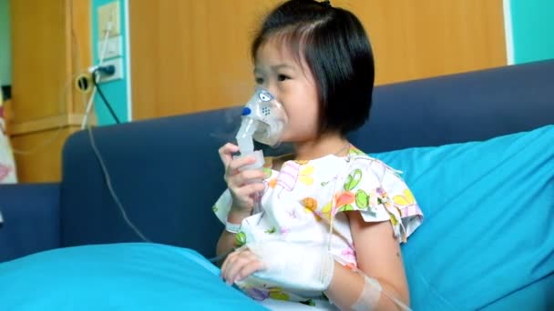 可爱的亚洲小孩带着口罩吸入气雾剂治疗哮喘 通过蒸汽雾化器呼吸 生病的女孩住院时 手上拿着盐水静脉注射 — 图库视频影像
