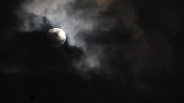 Karanlık gökyüzünde parlayan güzel dolunay. Gece Ay 'ın üzerinden hızla geçen kara bulutlar onu neredeyse gerçek zamanlı olarak saklıyor. Gece vakti dışarıda..