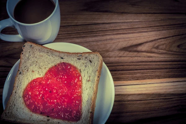 Delicious slice of bread with strawberry jam heart shape — Stock Photo, Image